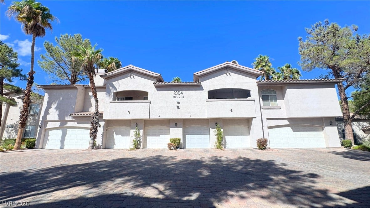 8304 Apple Glaze Avenue, #203, Las Vegas, NV 89145 Stucco exteriors and multiple garages define this multi-family residential building.