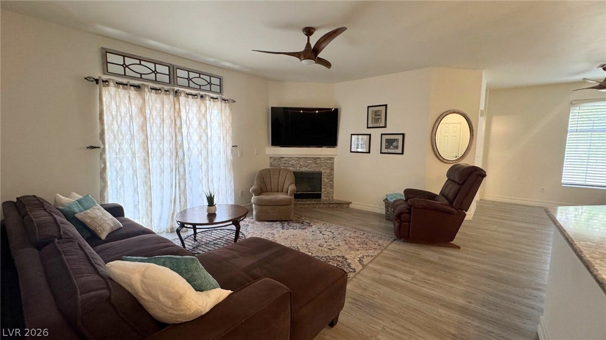 8304 Apple Glaze Avenue, #203, Las Vegas, NV 89145 A stone fireplace anchors this comfortable gathering area, complete with wood-look flooring and sliding doors.