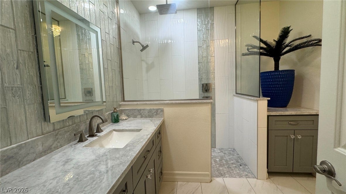 8304 Apple Glaze Avenue, #203, Las Vegas, NV 89145 Gleaming stone countertops and a modern walk-in shower define this contemporary primary bath.