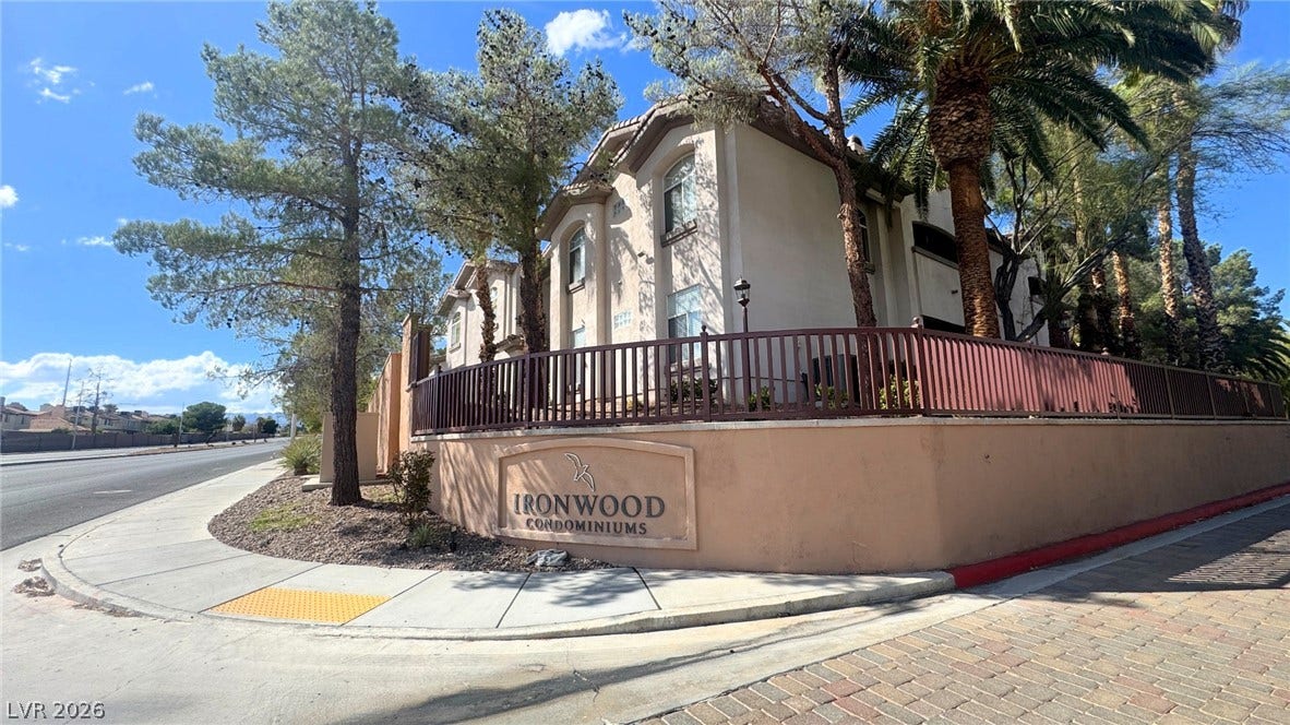 8304 Apple Glaze Avenue, #203, Las Vegas, NV 89145 Mature trees frame the stucco exterior of this multi-level residential building.