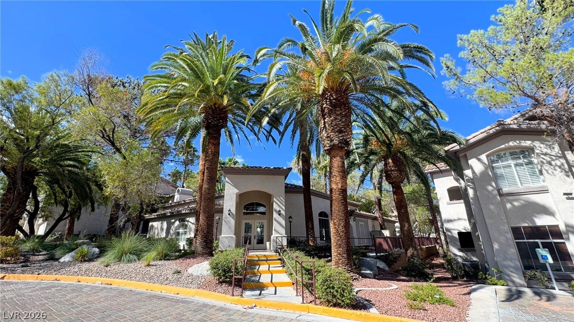 8304 Apple Glaze Avenue, #203, Las Vegas, NV 89145 Lush palm trees frame the concrete stairway leading to the classic tiled-roof entrance.