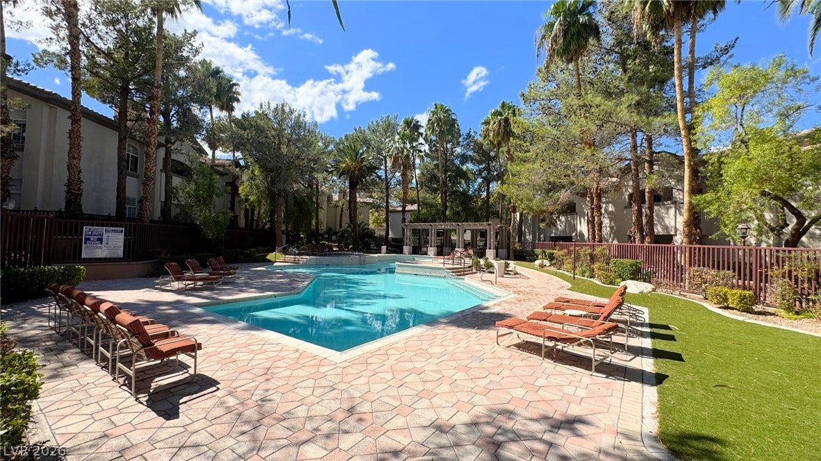 8304 Apple Glaze Avenue, #203, Las Vegas, NV 89145 Lush tropical palm trees frame a sparkling community swimming pool surrounded by paved decking.