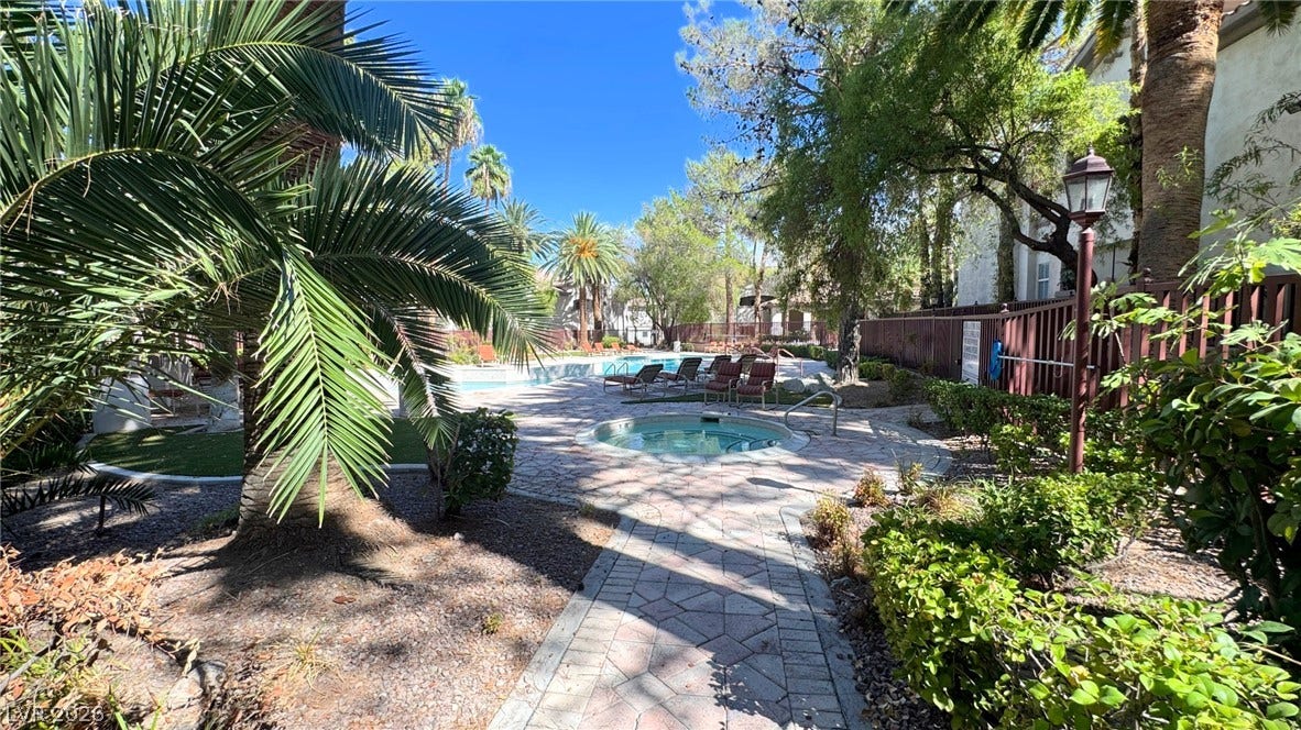 8304 Apple Glaze Avenue, #203, Las Vegas, NV 89145 Lush tropical landscaping surrounds a paved path leading to a built-in spa and pool area.