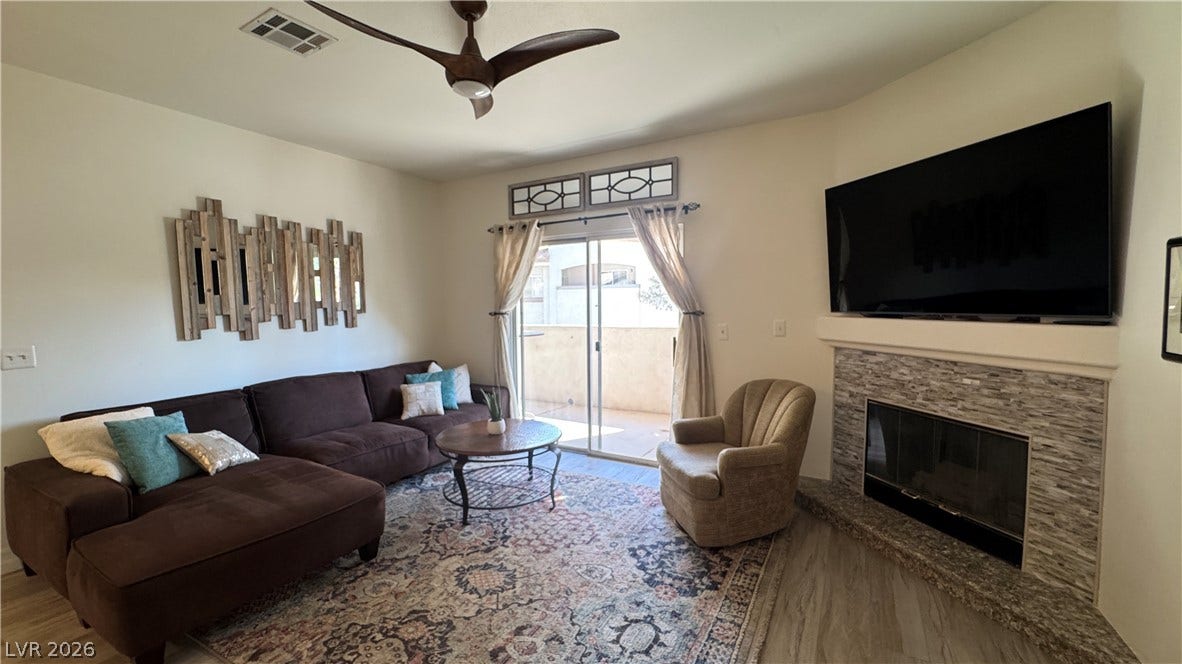 8304 Apple Glaze Avenue, #203, Las Vegas, NV 89145 An inviting stone fireplace anchors this comfortable living area with access to the patio.
