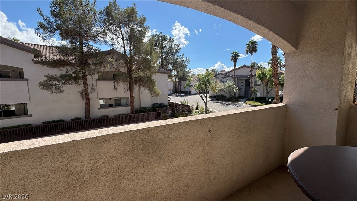 8304 Apple Glaze Avenue, #203, Las Vegas, NV 89145 An arched covered balcony looks out over the surrounding neighborhood under a blue sky.