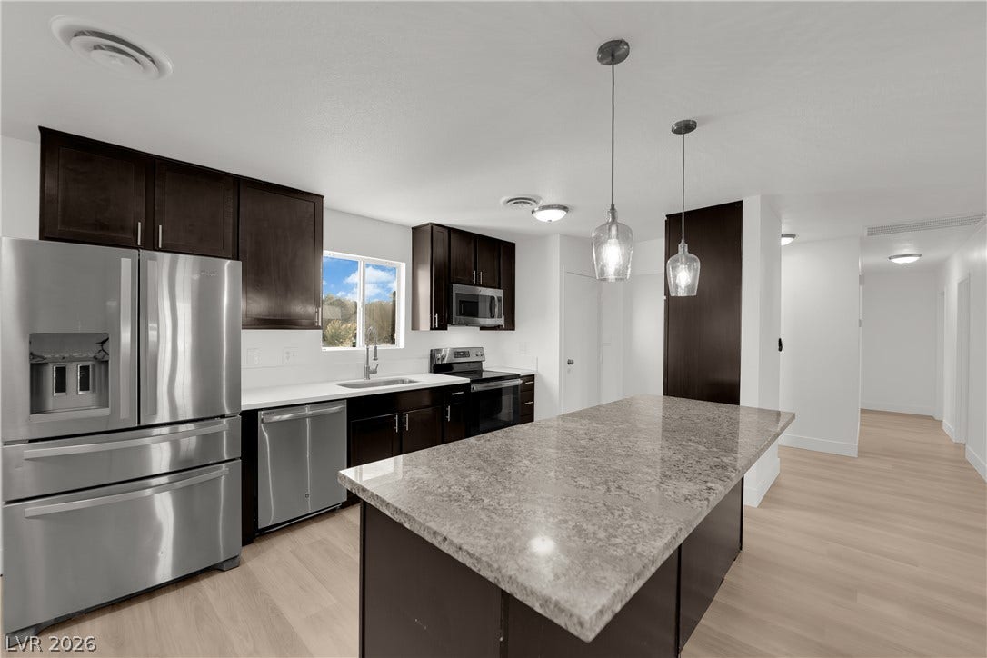 419 Scenic Drive, Henderson, NV 89002 Rich dark cabinetry and a polished stone island anchors this open culinary space.