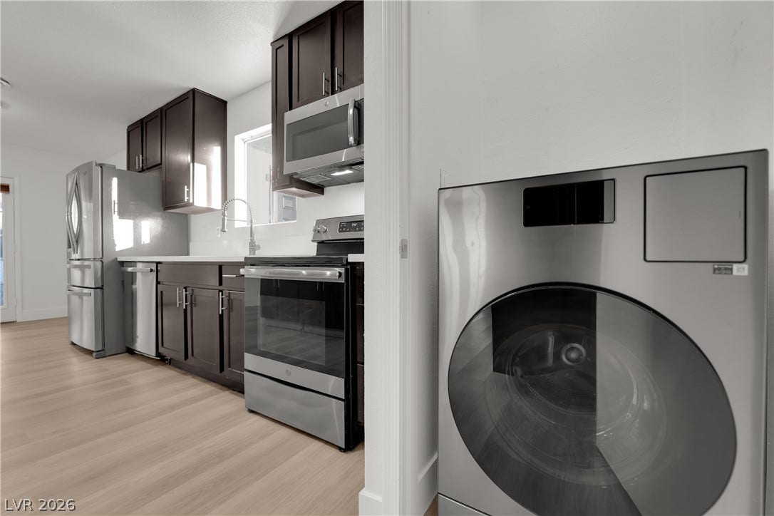 419 Scenic Drive, Henderson, NV 89002 A modern kitchen with dark cabinetry and stainless steel appliances flows into a laundry area.