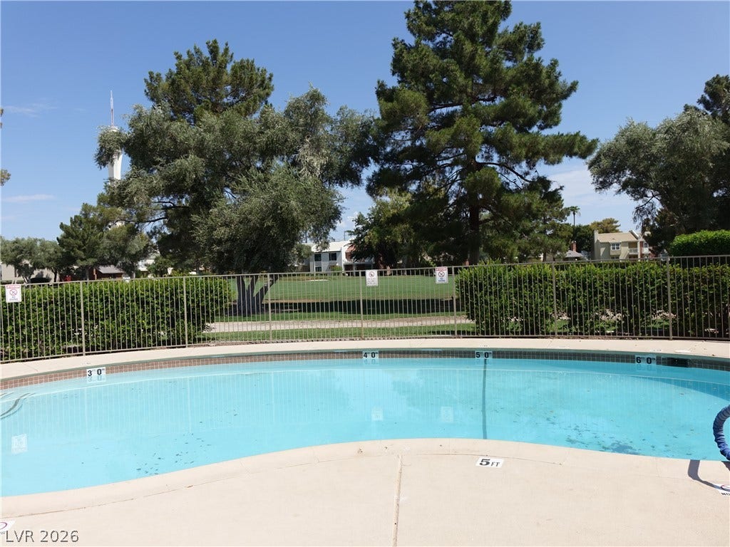 769 Oakmont Avenue, #403, Las Vegas, NV 89109 Mature trees frame the secure, fenced pool deck under clear blue skies.