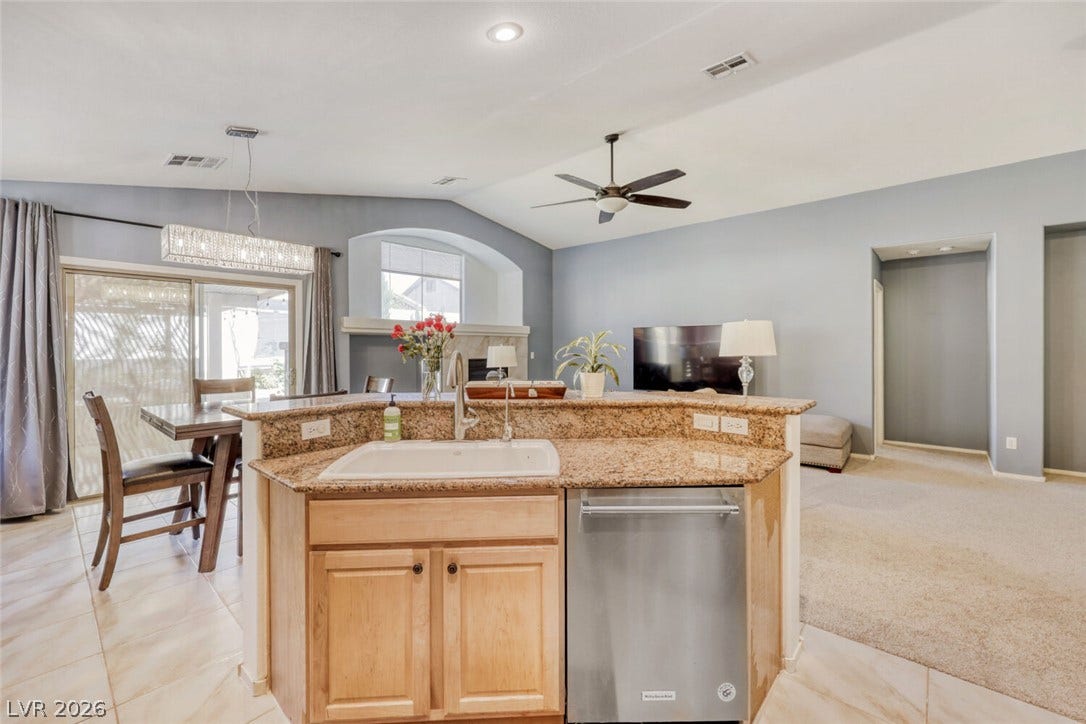 5817 Hawkeye Bell Street, North Las Vegas, NV 89081 An open layout connects the tiled kitchen to a vaulted living space with carpeted flooring.