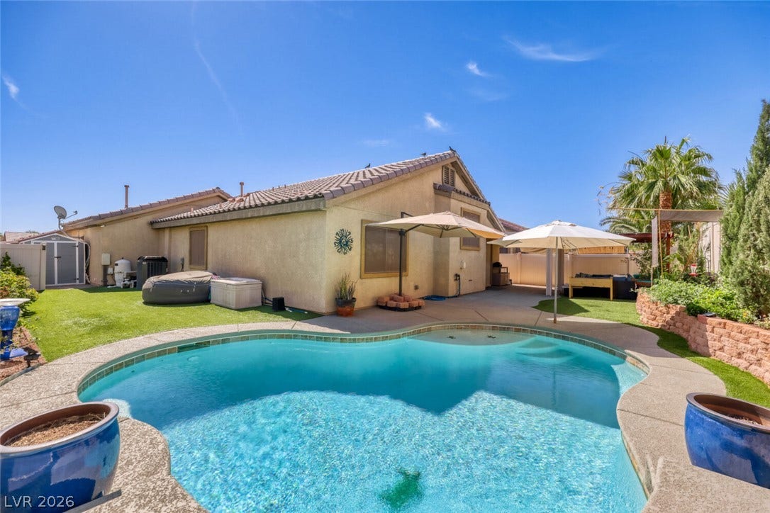 5817 Hawkeye Bell Street, North Las Vegas, NV 89081 An inviting backyard oasis features a shimmering custom pool surrounded by mature palm trees.