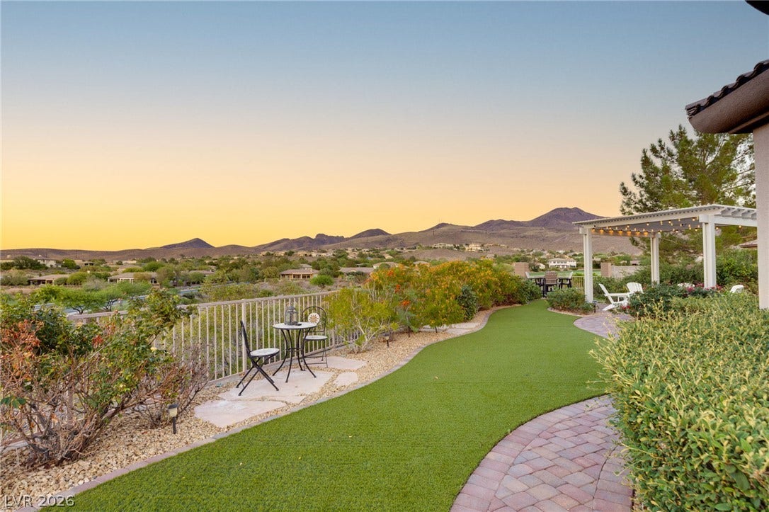 6 Brookridge Drive, Henderson, NV 89052 A curved brick pathway winds through manicured landscaping toward a pergola overlooking dramatic mountain ridges.