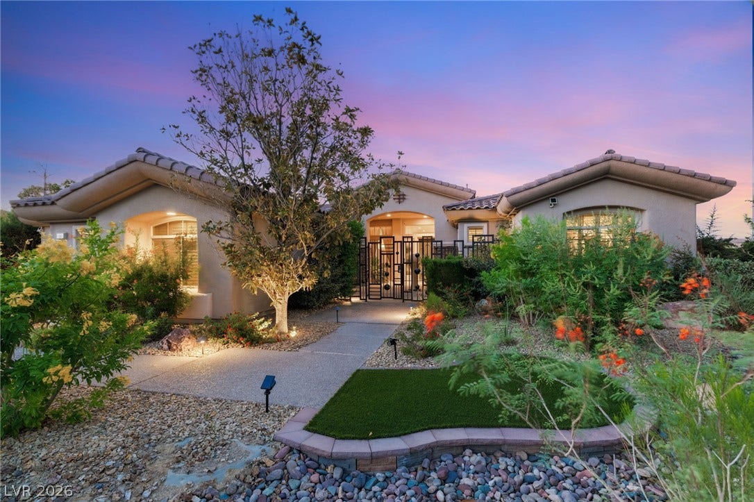 6 Brookridge Drive, Henderson, NV 89052 Lush desert landscaping leads to an inviting gated entryway under a dramatic sunset sky.