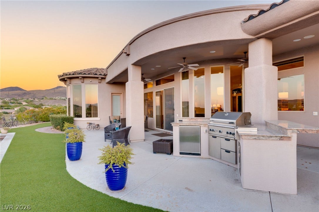 6 Brookridge Drive, Henderson, NV 89052 An expansive covered patio provides a built-in outdoor kitchen alongside manicured turf and desert views.