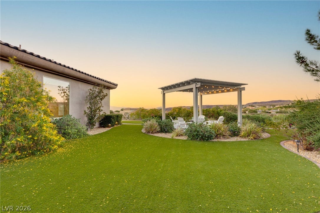 6 Brookridge Drive, Henderson, NV 89052 A spacious lawn area features a modern pergola and scenic mountain views at sunset.
