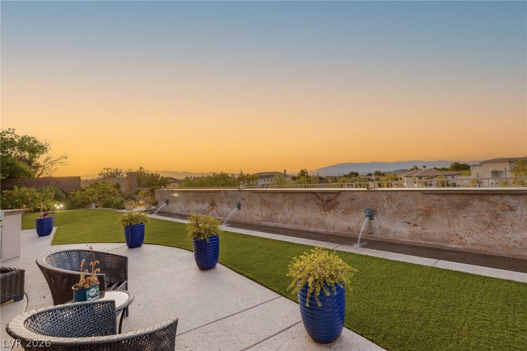 6 Brookridge Drive, Henderson, NV 89052 Manicured lawns and water features frame sweeping mountain views during a golden sunset.