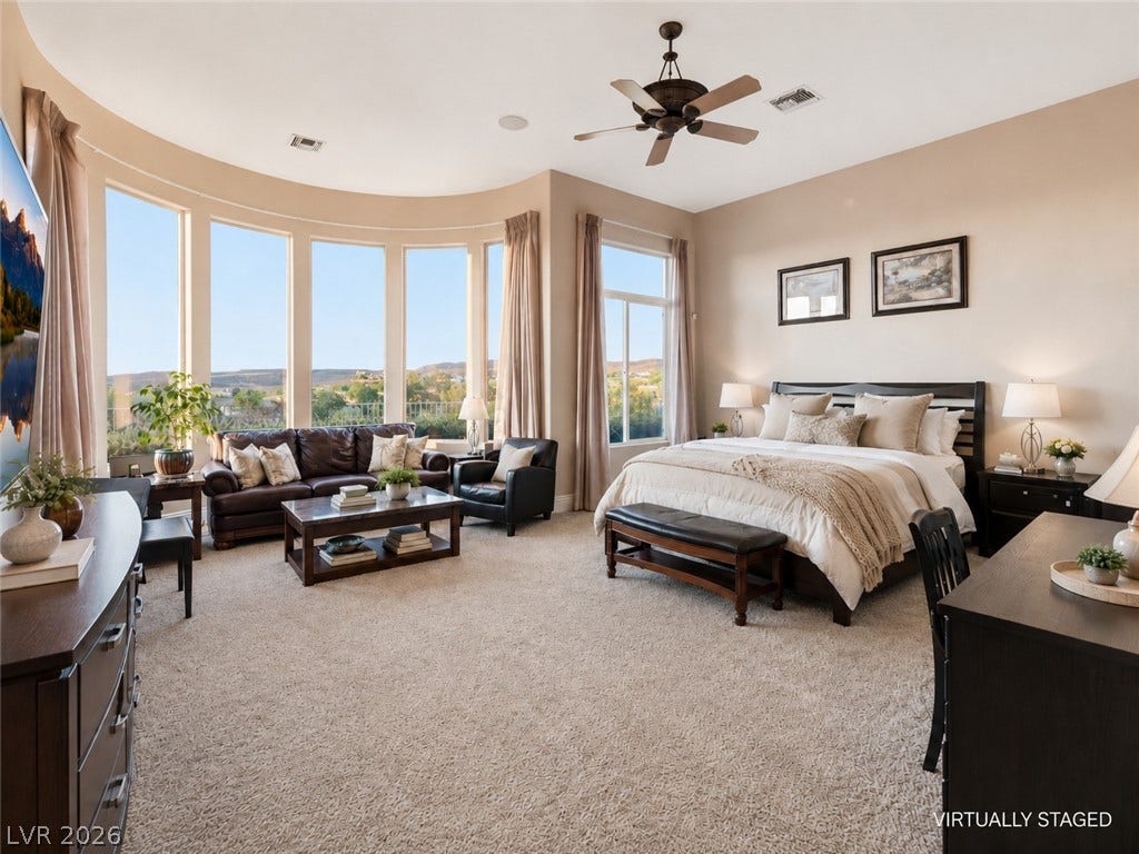 6 Brookridge Drive, Henderson, NV 89052 Expansive windows frame panoramic hill views in this spacious primary bedroom with plush carpeting.