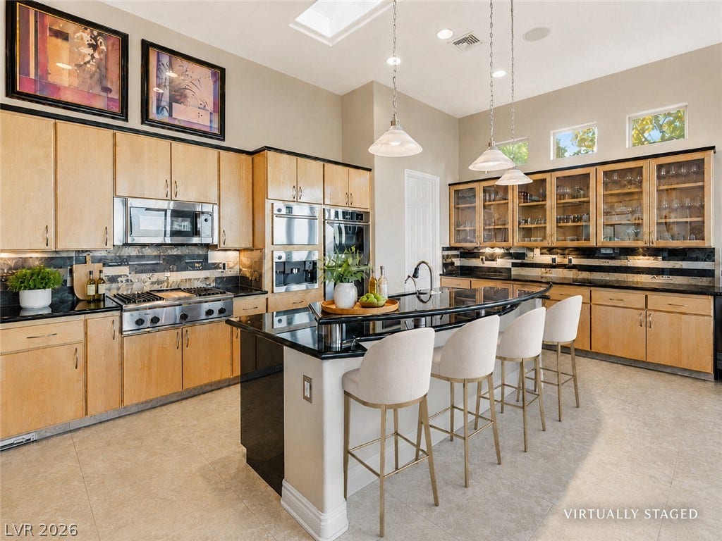 6 Brookridge Drive, Henderson, NV 89052 Ample natural light illuminates this spacious kitchen featuring a central island and warm wood cabinetry.
