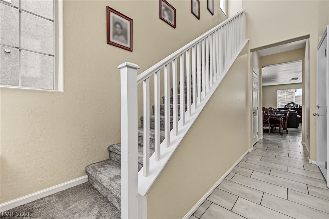3813 Birch River Street, North Las Vegas, NV 89032 A classic staircase with white railings transitions seamlessly into the tile-floored hallway.