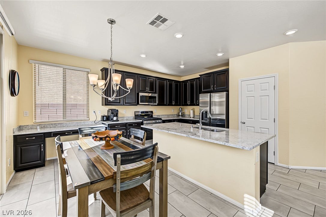 3813 Birch River Street, North Las Vegas, NV 89032 Dark cabinetry and light granite countertops anchor this kitchen designed with a central prep island.