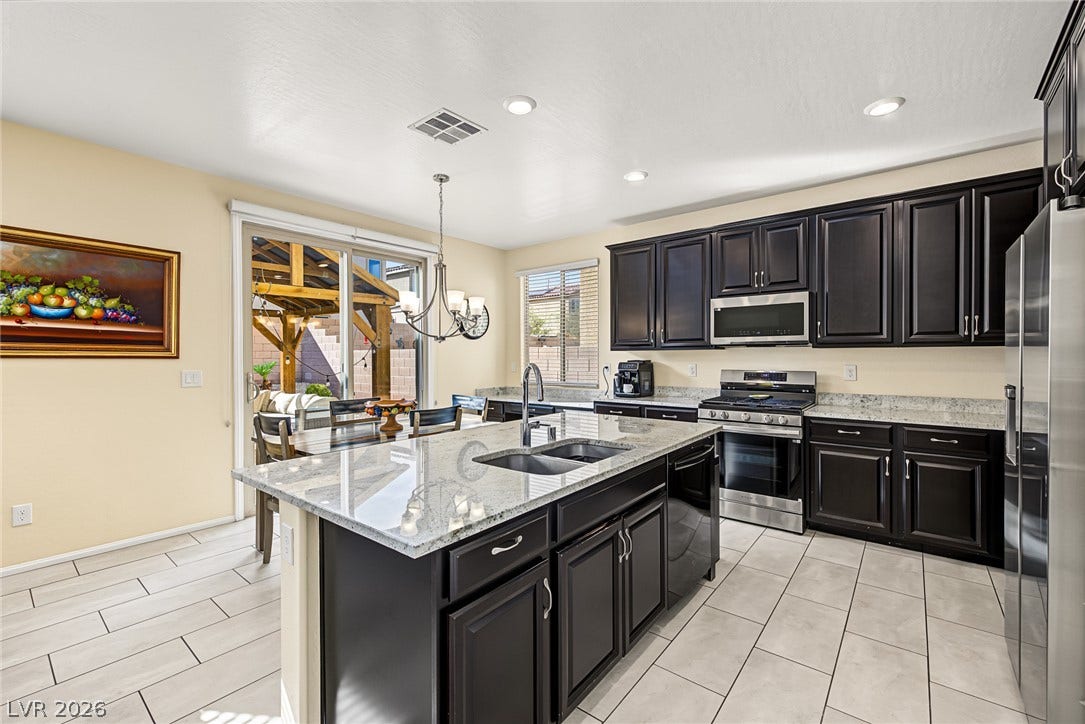 3813 Birch River Street, North Las Vegas, NV 89032 Polished granite countertops and dark cabinetry anchor this open, tile-floored culinary space.