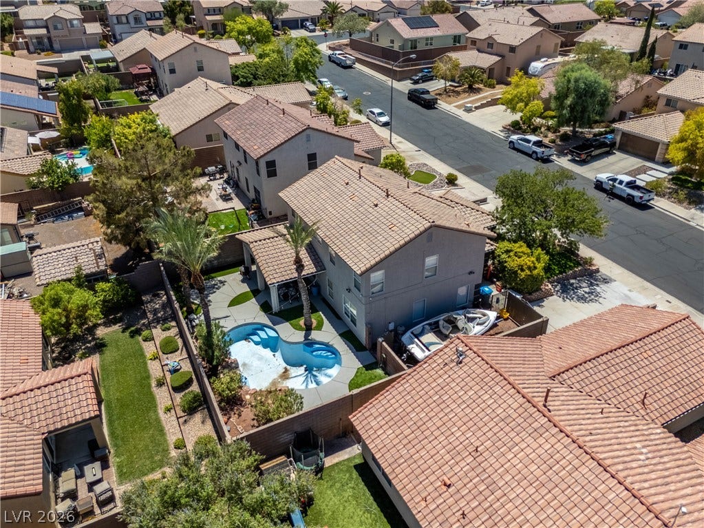 An aerial perspective reveals a two-story home with a private backyard pool and tile roof.