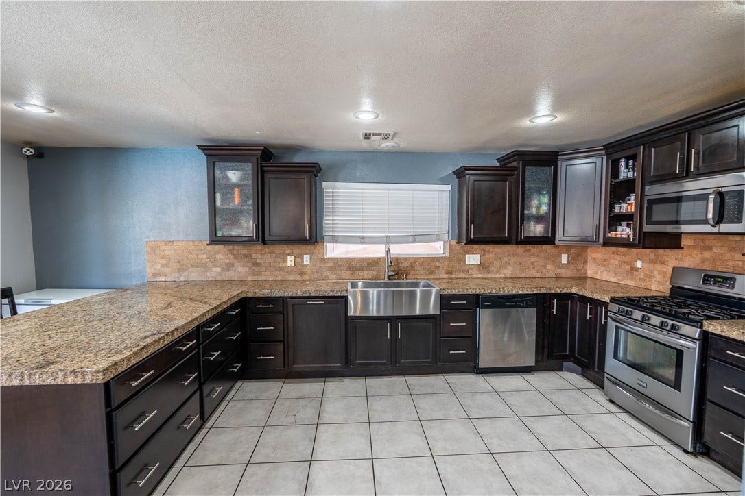 Rich dark cabinetry pairs beautifully with expansive stone countertops and tile flooring in this kitchen.