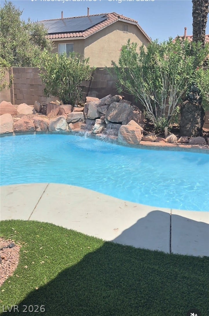 Natural rock formations with an integrated waterfall border this sparkling backyard swimming pool.
