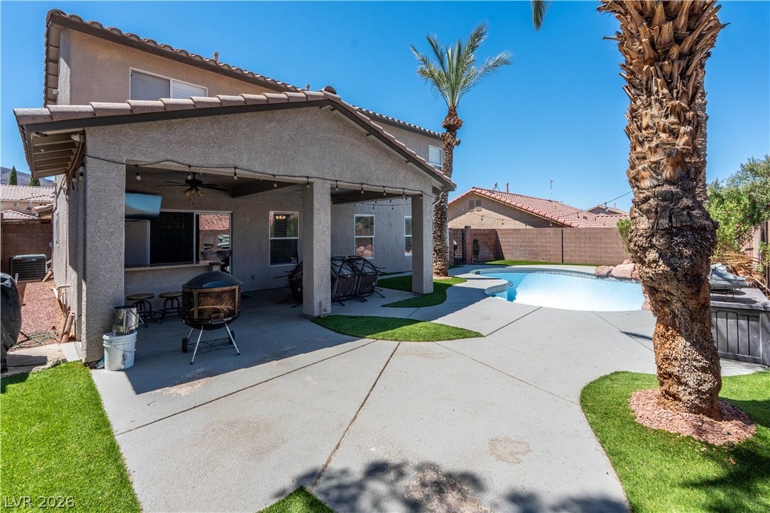 A spacious concrete patio and covered porch overlook the sparkling private pool.