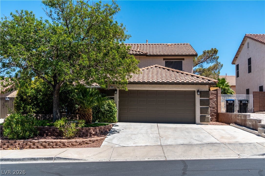 Spanish tile roofing and a wide concrete driveway frame this classic suburban exterior.