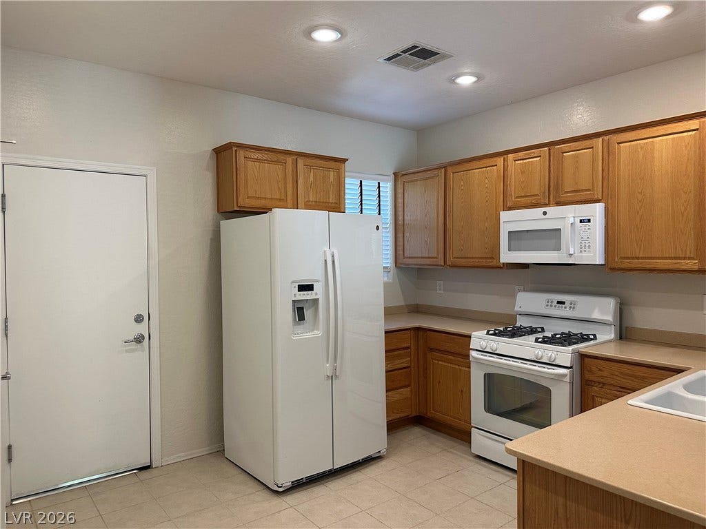 2488 Galaxy Cluster Street, Henderson, NV 89044 Kitchen boasts Corian Counters, Upgraded Cabinets, Nook, Recessed Lighting, Pantry, Tile Flooring, Gas Stove, Dishwasher, Microwave, and Refrigerator