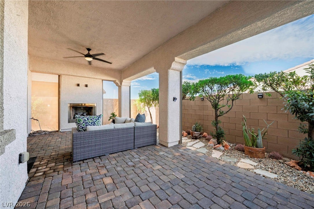 An inviting covered patio features durable paver flooring and an integrated outdoor fireplace.