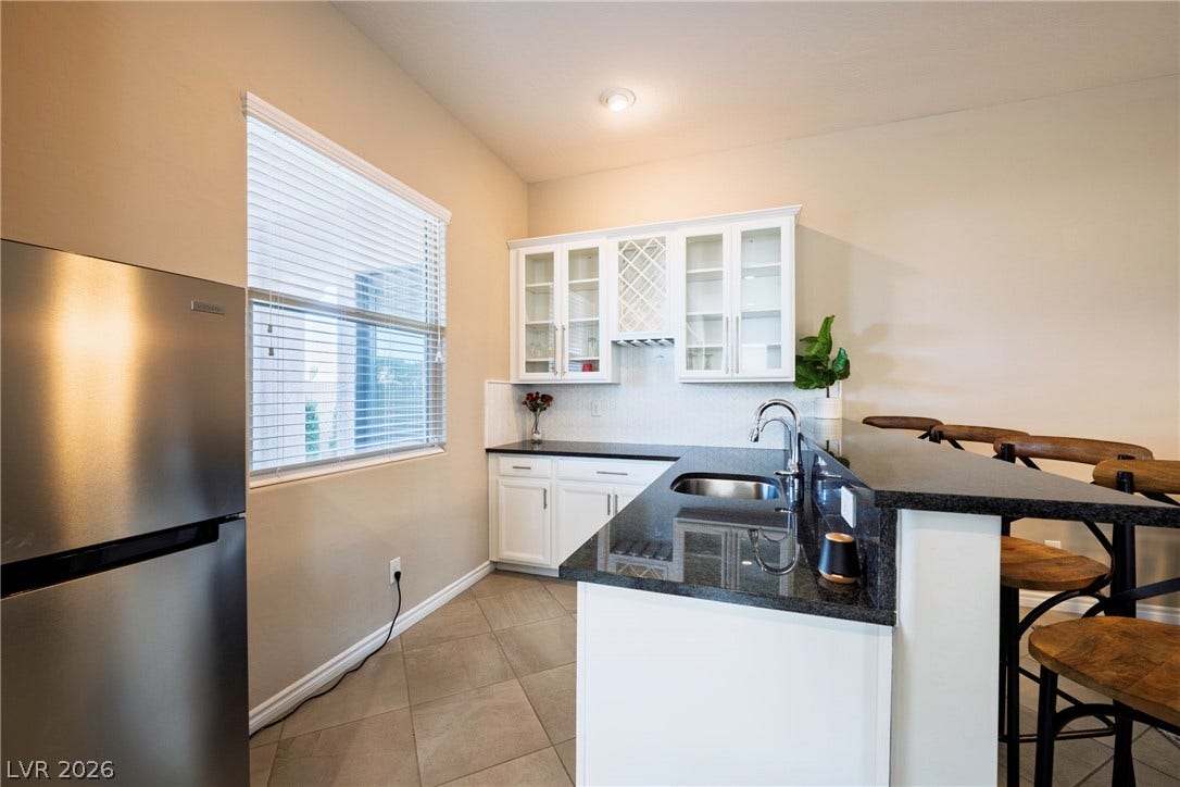 Gleaming stone countertops and classic tile flooring define this stylish wet bar area.