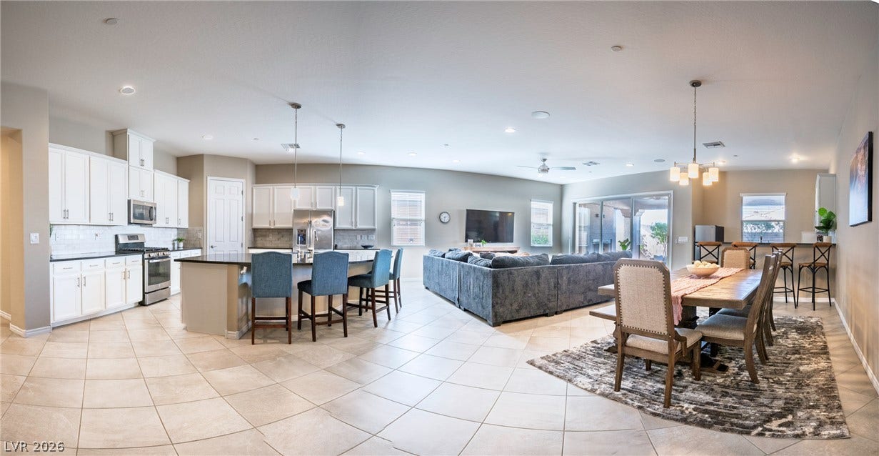 An open floorplan seamlessly connects the kitchen, dining, and living areas over tiled flooring.