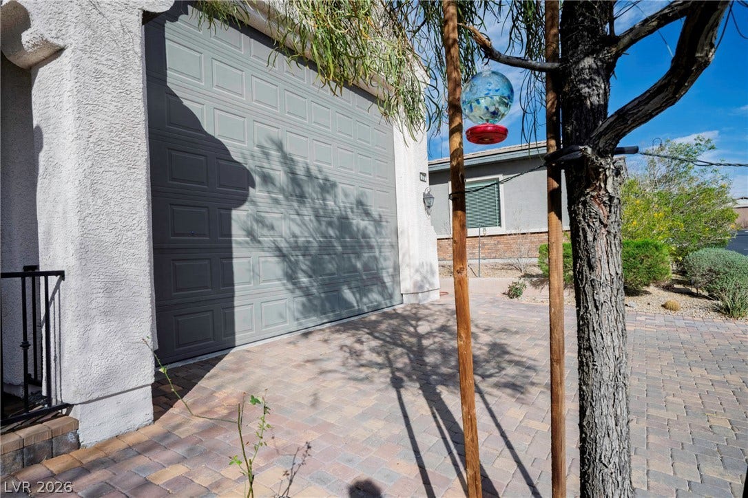 An integrated multi-car garage fronts a paved driveway under clear blue skies.