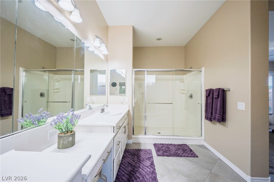 A spacious double vanity balances the sleek walk-in shower in this modern bathroom setup.