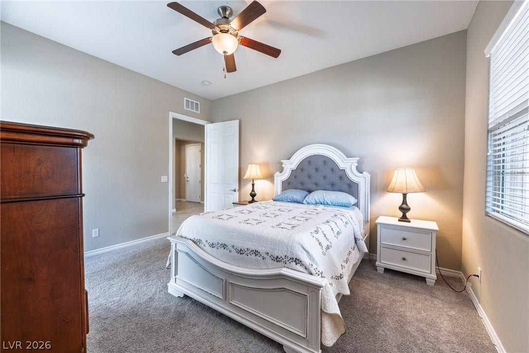 Plush carpeting and high ceilings define this inviting bedroom space.