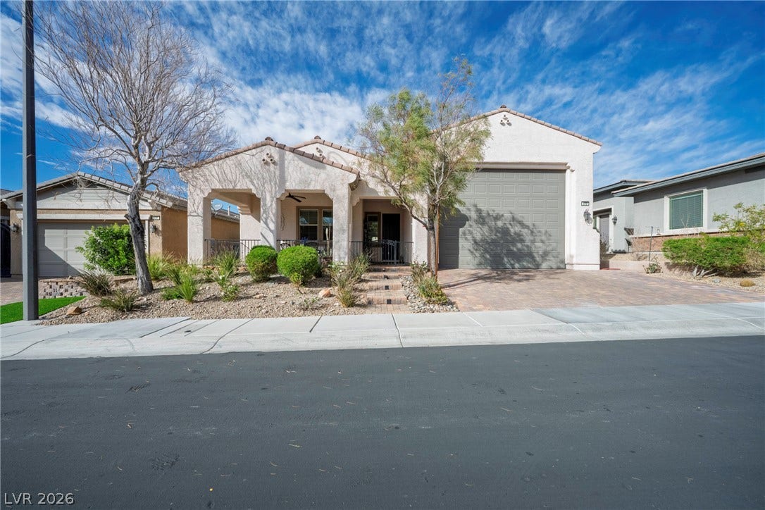 Desert landscaping and a paved driveway frame this single-level home with stucco exterior finishes.
