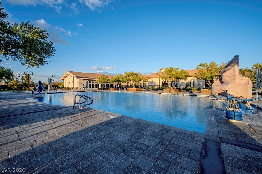 An expansive community swimming pool is surrounded by extensive stone paver decking and landscaped grounds.