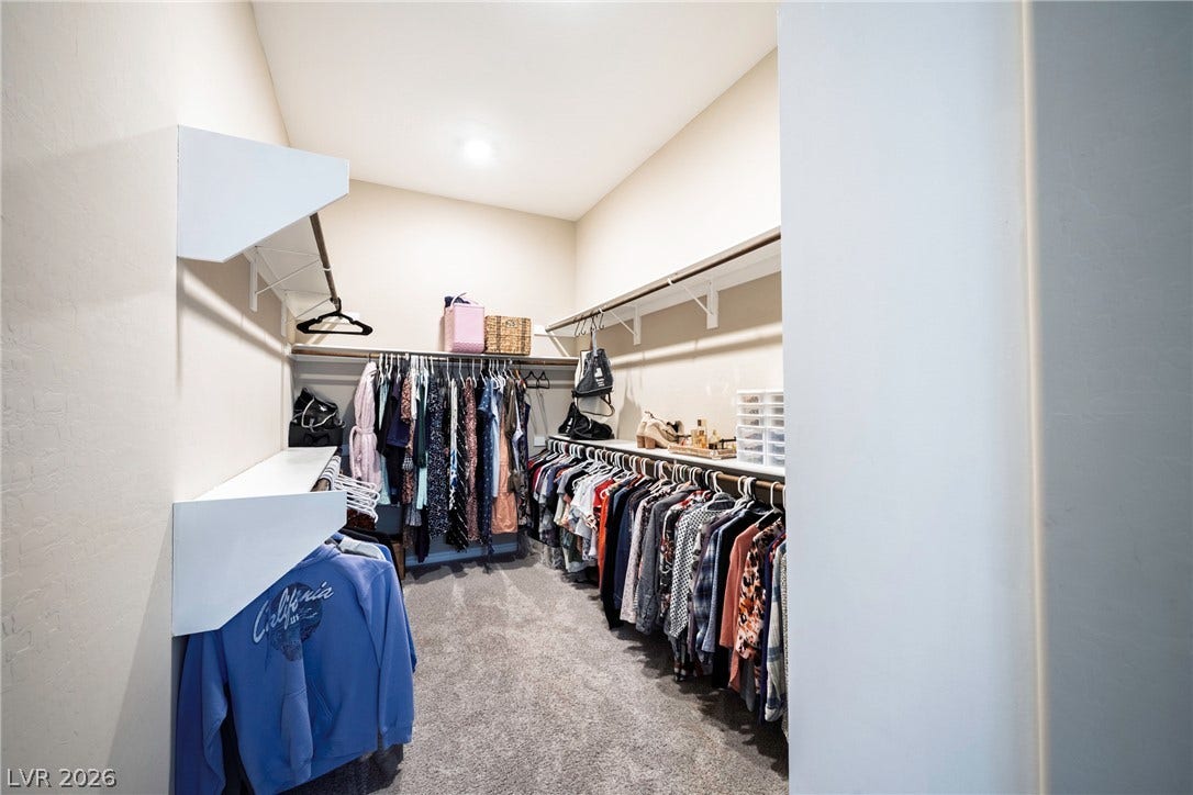 Ample hanging rods and built-in shelving maximize storage space in this carpeted walk-in closet.