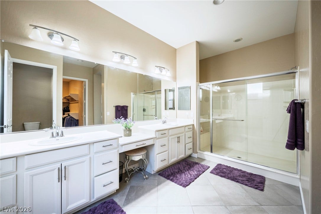 An expansive double vanity and glass-enclosed shower highlight this tiled primary bath.