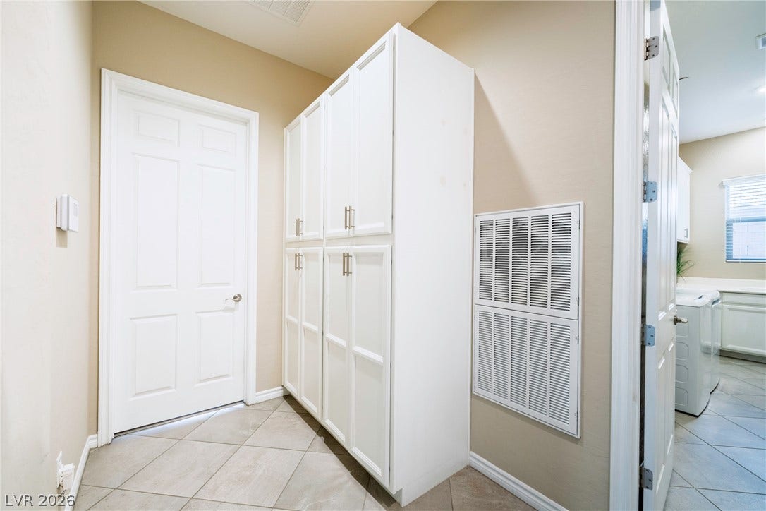 Floor-to-ceiling storage cabinets flank the tiled hallway leading toward a functional utility space.