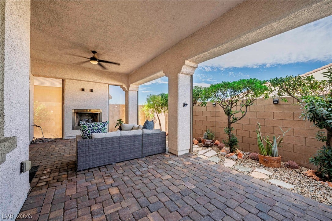 A covered brick patio features a cozy fireplace next to a landscaped courtyard.