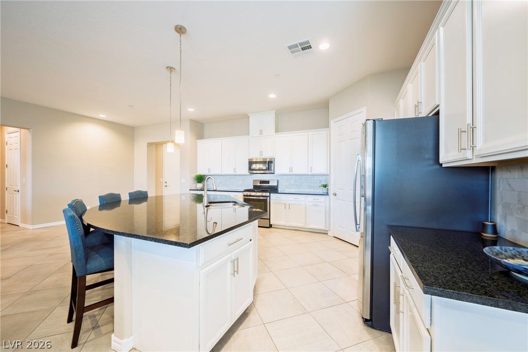Polished stone counters and abundant white cabinetry highlight this functional culinary space.
