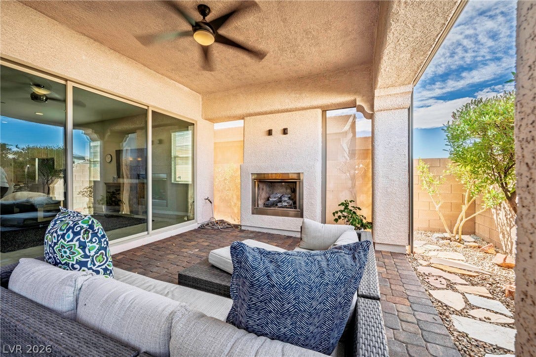 An inviting outdoor fireplace highlights this covered patio featuring durable paver flooring.