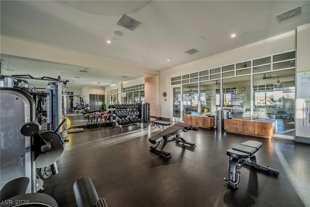 A spacious fitness facility features high ceilings, recessed lighting, and expansive wall mirrors.