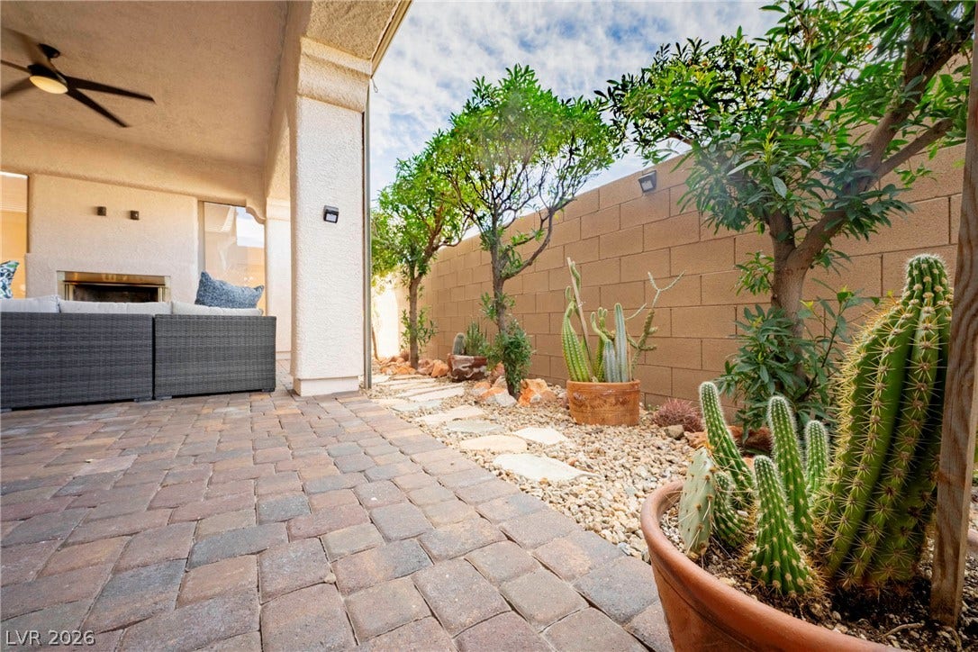 An inviting covered patio features warm brick pavers alongside a low-maintenance desert landscape.