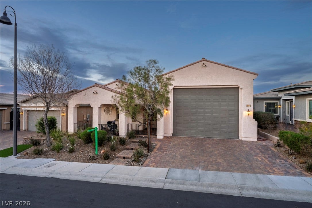 Spanish tile rooflines and a brick paver driveway enhance this desert-landscaped facade.