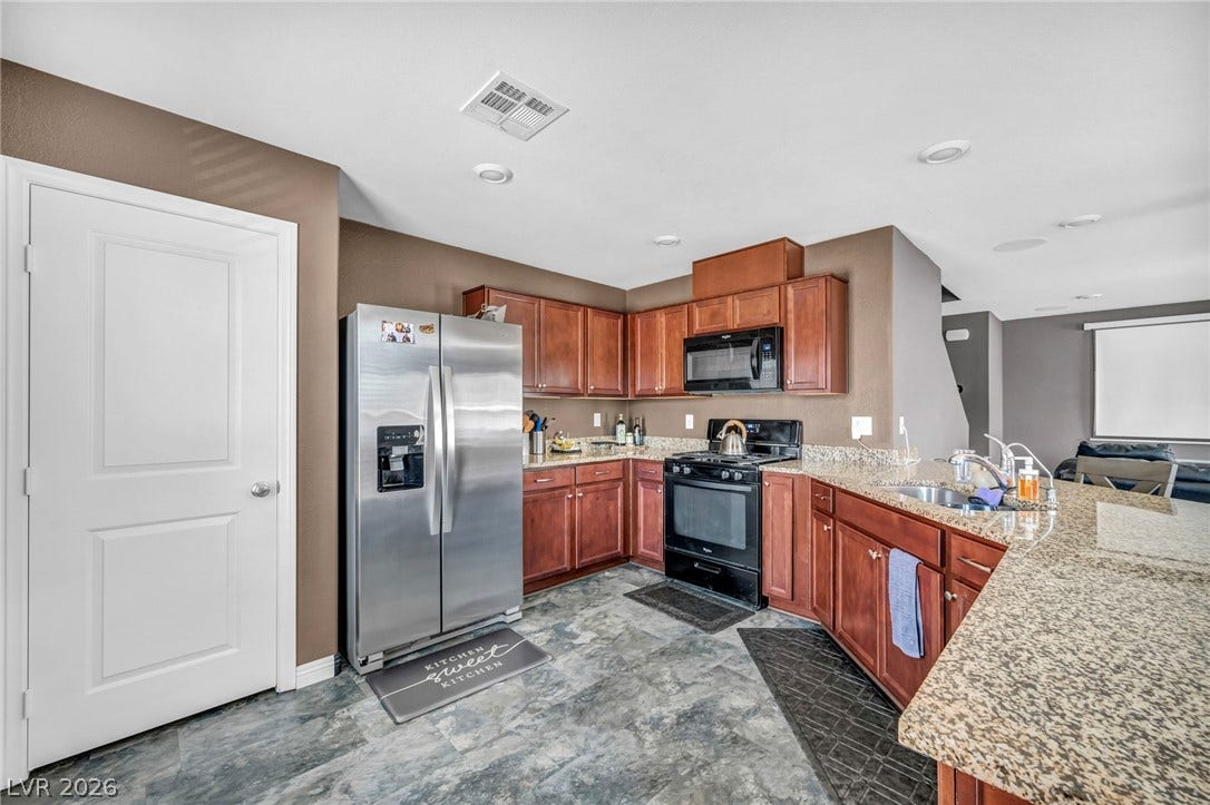 1205 Deep Valley Avenue, North Las Vegas, NV 89084 Rich wood cabinetry and stone countertops anchor this modern culinary workspace with an open layout.