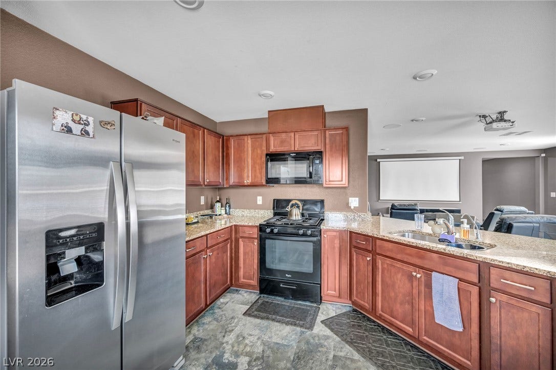 1205 Deep Valley Avenue, North Las Vegas, NV 89084 Rich wood cabinetry paired with stone countertops defines this open-concept kitchen space.