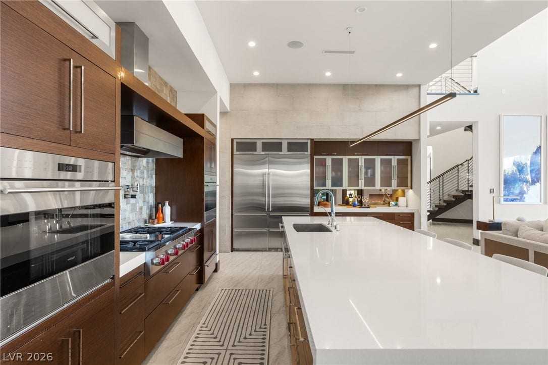 1269 Imperia Drive, Henderson, NV 89052 Rich wood cabinetry contrasts beautifully with expansive white stone countertops in this modern kitchen.